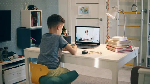 A boy is taking notes while studying online from home Video stock 142627860