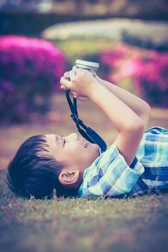 Boy taking photo by camera, exploring nature at park. Active lifestyle Stock Photos