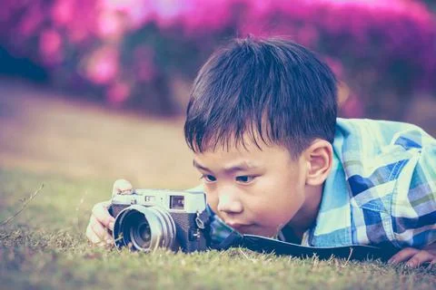 Boy taking photo by camera, exploring nature at park. Child in nature Stock Photos