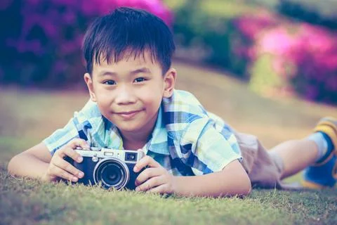 Boy taking photo by camera, exploring nature at park. Active lifestyle Stock Photos