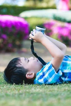 Boy taking photo by camera, exploring nature at park. Active lifestyle. Stock Photos