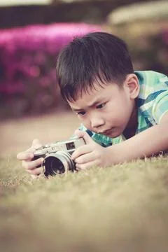 Boy taking photo by camera, exploring nature at park. Child in nature Stock Photos