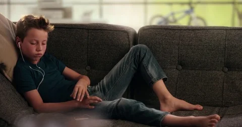 Boy is taking a smartphone from the couch Stock Footage 78857775