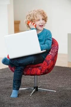 Boy talking on a mobile phone and using a laptop Stock Photos