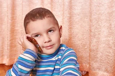The boy is talking on the phone with a sad expression. Stock Photos