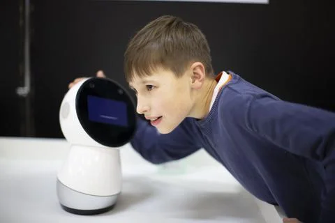 Boy talking, playing with android robot at the exhibition Stock Photos