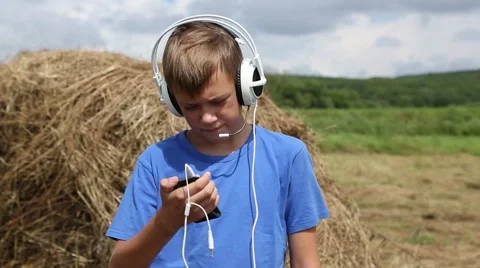 Boy talking on a smartphone outdoors on background haystack Stock Footage 53416919