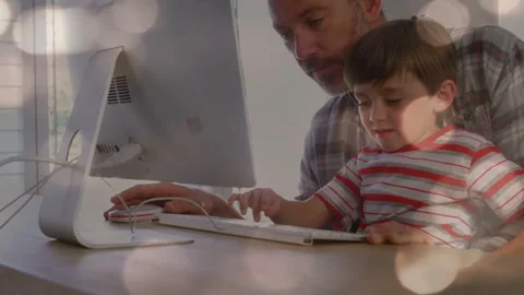 Boy tapping white keyboard, father guiding hand and moving wired mouse, sharing Stock Footage 333911290