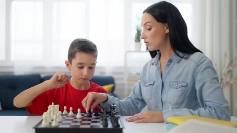 Boy teaching mother to play chess, game for concentration and memory improvement Stock Footage 224960214