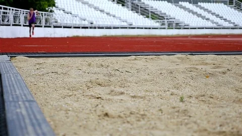 Boy teenager doing long jump landing in sandpit, slow motion, low angle Stock Footage