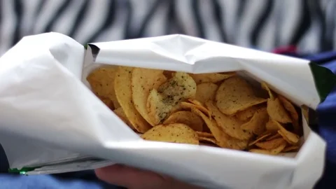 Boy teenager eating potato chips with hands on sofa at home unhealthy food Stock Footage