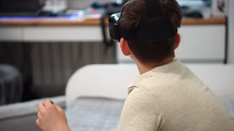 Boy ten years old using virtual reality helmet sitting on bed in his room. close Stock-Footage 307490367
