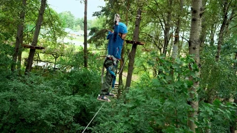 A boy is testing on a rope trail in the park with special climbing equipment. Stock Footage 160685586
