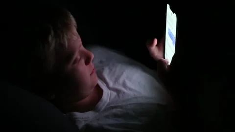 Boy texting on a cell phone in the dark Vídeos de archivo 135690883