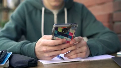 Boy texting on smartphone sitting in cafe in city Stock Footage 75595399