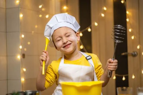 Boy think about future baking, cooking in kitchen, wearing apron and caps for Stock Photos