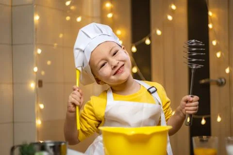 Boy think about future baking, cooking in kitchen, wearing apron and caps for Photos