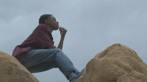 Boy thinking on top of rock formation. Video stock 27345857