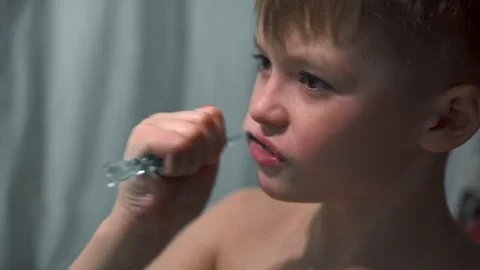 The boy thoroughly brushes his teeth in the bathroom Stock Footage 85117505