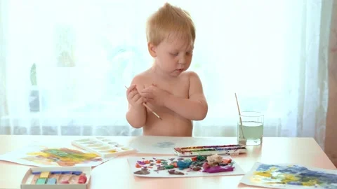 Boy three years scratched himself and continued to paint on white paper Stock Footage 130570560