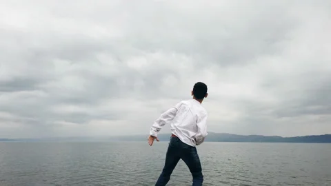 Boy throw jumping stones on water surface Stock Footage 160907704