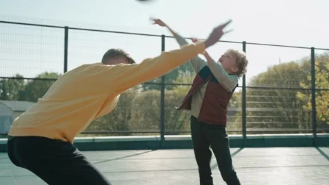 Boy throwing ball playing with father on the basketball court on a sunny day Vídeo Stock 166834920
