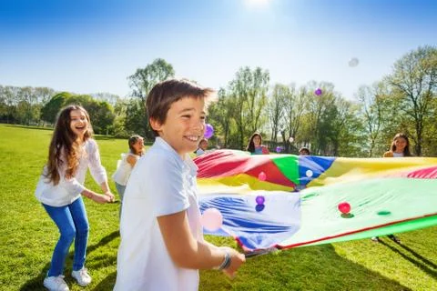 Boy throwing balls up by using rainbow parachute Foto stock