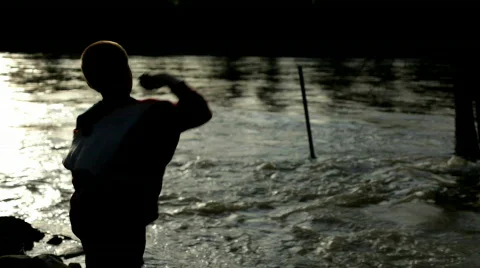 Boy throwing rocks into water at Sunset 스톡 동영상 684861