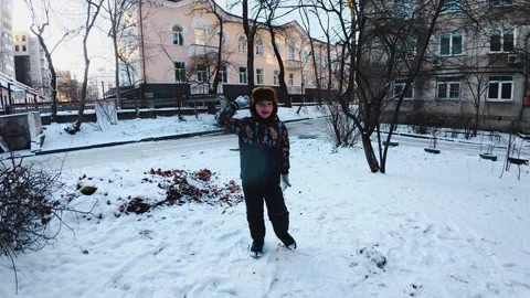 Boy Throwing Snowball Toward Camera in Courtyard During Winter Walk Stock Footage 327077564