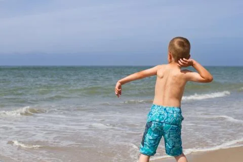 Boy throwing stone into the ocean Stock Photos
