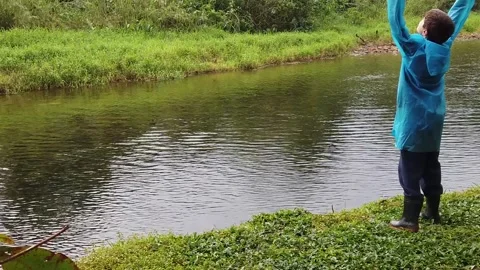 Boy throwing a stone into the river Stock Footage 275304536