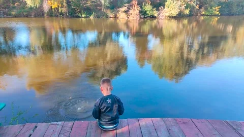 Boy throwing stone into the river in rain forest. Stock Footage 163669304