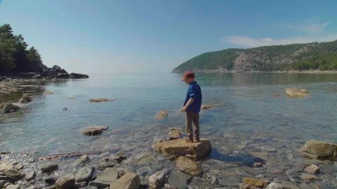 A boy throwing a stone into the water on the beach. Montenegro. Stock Footage 274732896