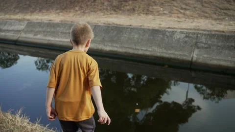 Boy throwing a stone into the water Stock-Footage 203873815