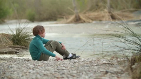 Boy throwing stones into the river Stock Footage 197902285