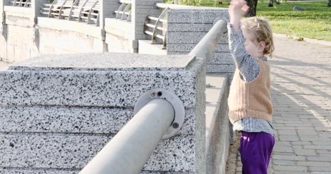 Boy throws pebbles into the water on a sunny day. Stone city of concrete, metal 動画素材 274911250