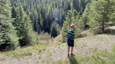 A boy throws a rock over a mountain cliff overlook in Idaho Vídeos de archivo 132191743
