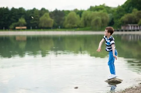 Boy throws small stone into the lake Stock Photos