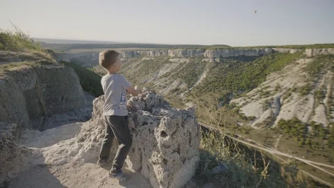 Boy throws a stone from the top of the mountain. Nature landscape. Peaceful Stock Footage 94849332