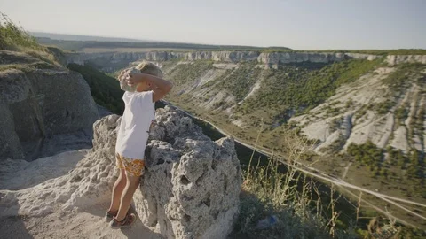 Boy throws a stone from the top of the mountain. Nature landscape. Peaceful Stock Footage 94849366