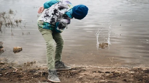 The boy throws stones that bounce off the surface of the water Stock Footage 128016507