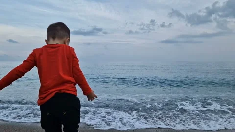 A boy throws stones into the sea Stock Footage 286427211