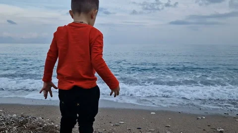 A boy throws stones into the sea Stock Footage 286427508