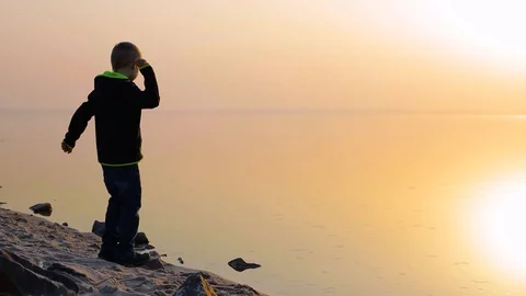 Boy throws three stones into the water Stock Footage 127437615