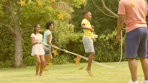 Boy timing jumps to rope swing while two adults turning rope for recreation, Stock Footage 333594870