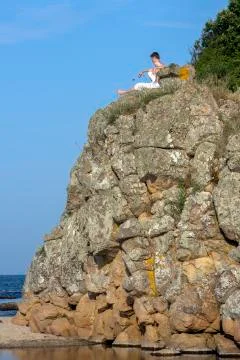 Boy at the top of a cliff between the river and the sea on the shore. Stock Photos