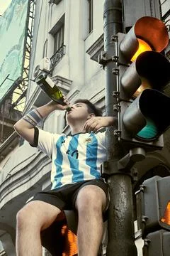 A boy on top of a traffic light drinking to celebrate Stock Photos