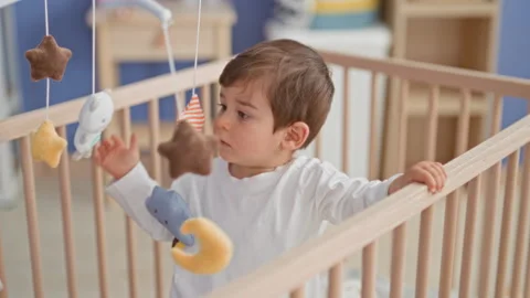 Boy touching hanging plush toy mobile with his hand while standing in a woo.. Stock Footage 337433501