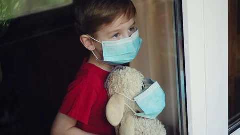A boy with a toy in a mask waves out the window Stock-Footage 129336868