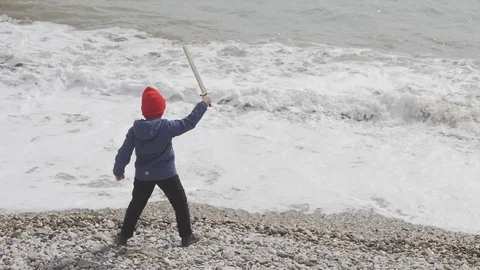 Boy with a toy sword in hand on a background of waves Stock Footage 88441634